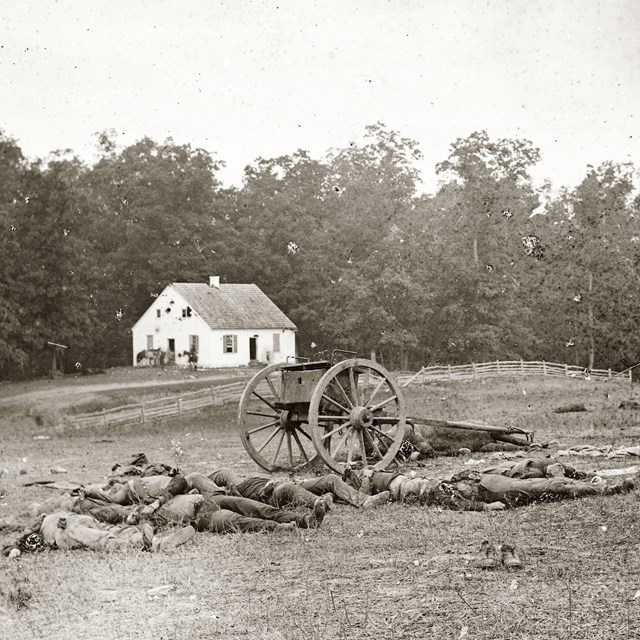 A historic black and white photo of the Dunker Church and Confederate dead.