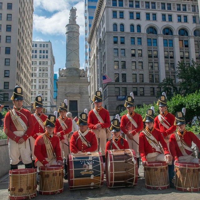 Field musicians posing with Baltimore Battle Monument in background