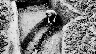 A man in a ditch looking at the remains of the original Fort Necessity stockade