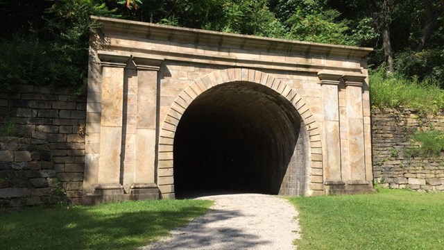 A railroad tunnel exterior decorated with pillars. 