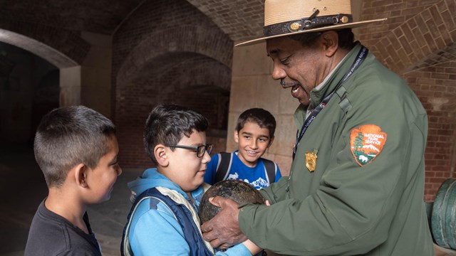 ranger and students hold canon ball