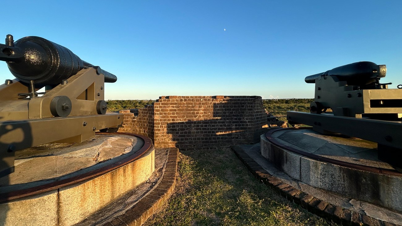 Two cannons on top of a granite and brick structure.