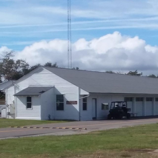 Long white building with multiple garage bays on a cloudy day
