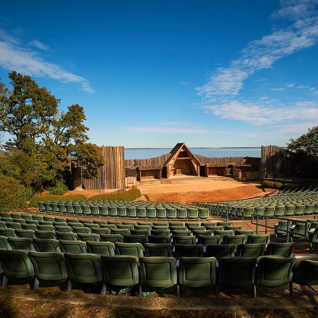 Outdoor amphitheater with rows of seats leading to a stage set.