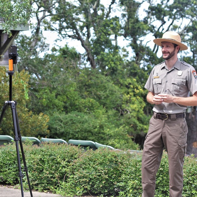 Ranger stands outdoors facing a phone on a tripod