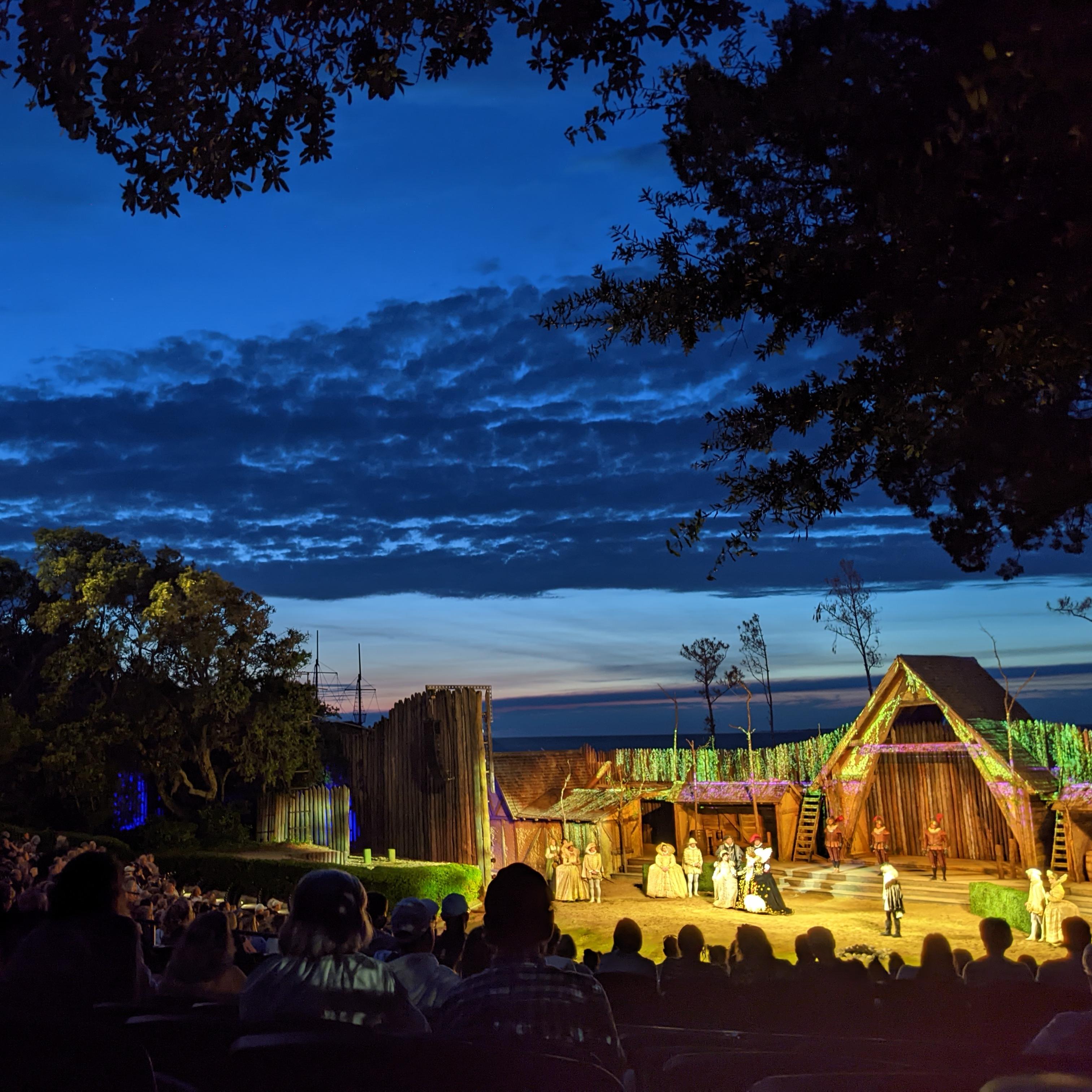 Outdoor amphitheater with rows of seats leading to a stage set.