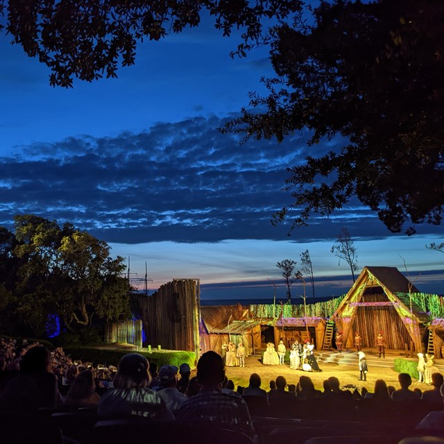 Outdoor amphitheater with rows of seats leading to a stage set.