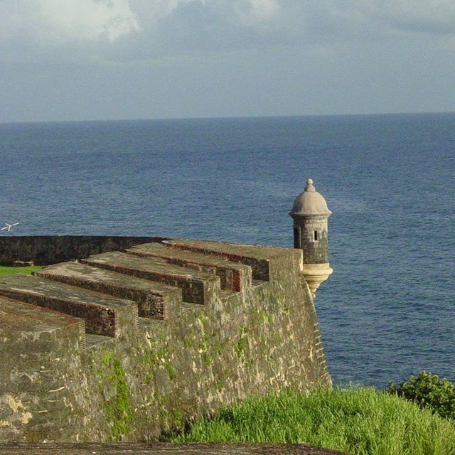 a mason wall runs into a blue ocean and sky