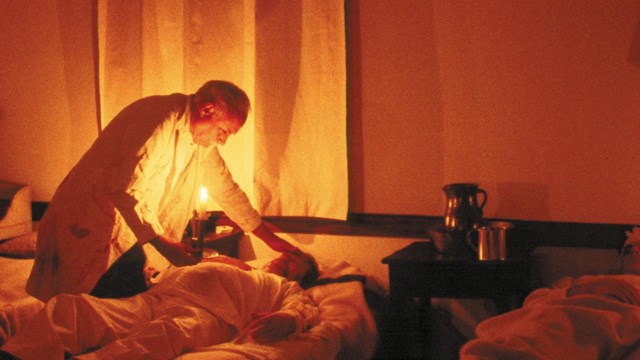 Surgeon treating a patient in a hospital bed