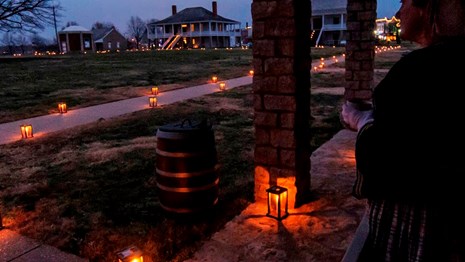 Lady looks out over parade ground lined with candle lanterns