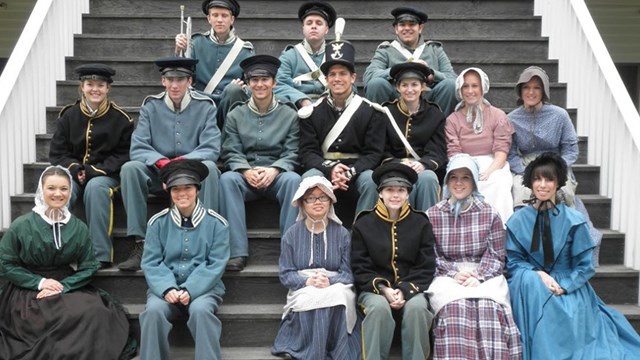 Young people dresssed in period costume sitting on stairs