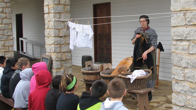 Laundress reenactor talking to 4th graders