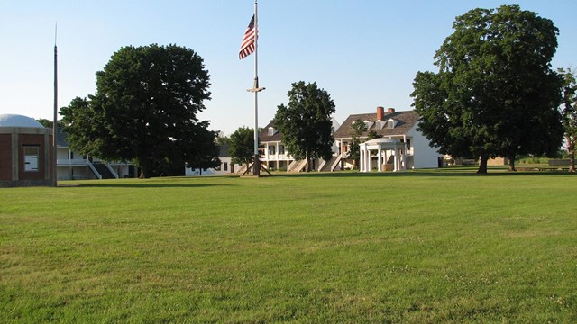 grassy field with flagpole and buildings in background