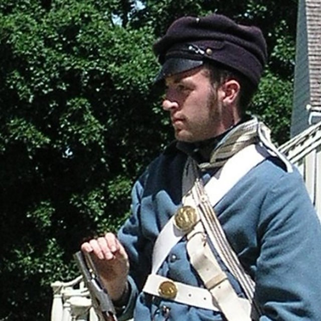 An interpreter in 1840s US infantry dress holding a period long rifle