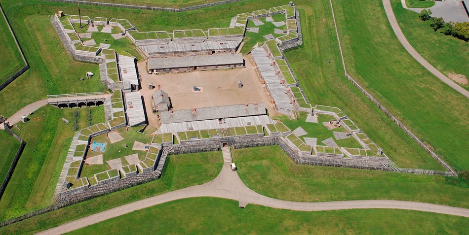 A view of the fort from above. A wooden star-shaped building sits in the middle of a grass field.