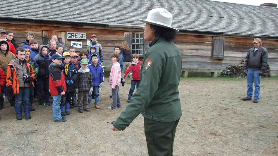 Several children stand in a line. They are dressed in 18th C costumes.