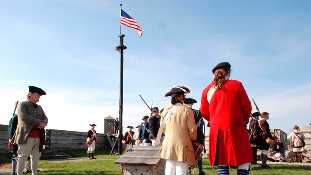 Soldiers stand saluting a flag.