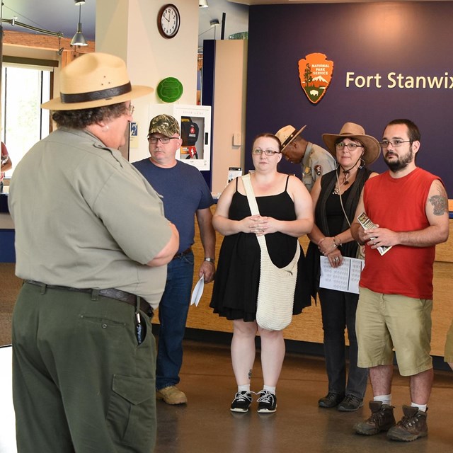 A park ranger stands in front of a group of visitors. 
