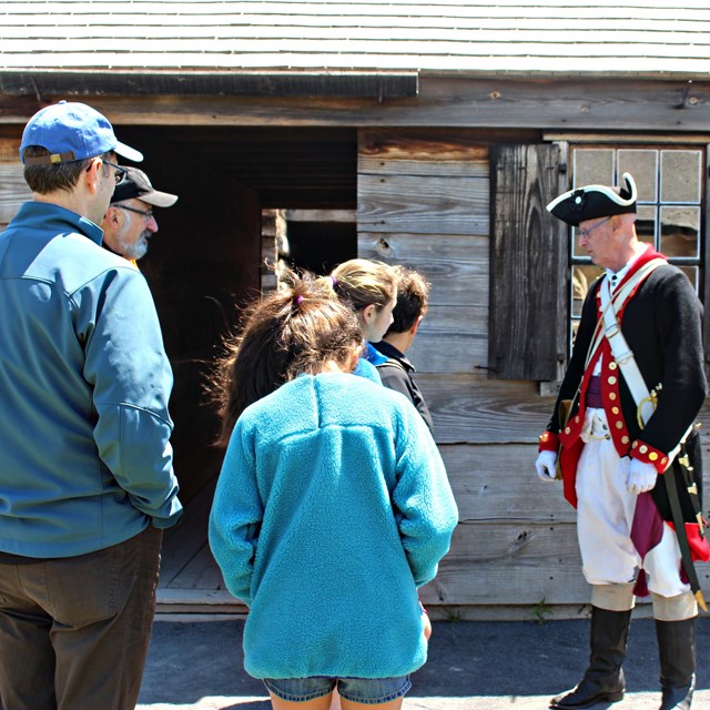 Several visitors speak with a Continental soldier. 
