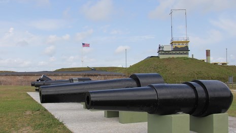 exterior side view of Fort Moultrie with row of Civil War cannon lined up in front.