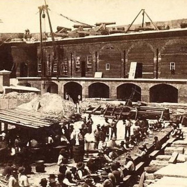 The interior of Fort Sumter, with men seated at a long table in the low center.
