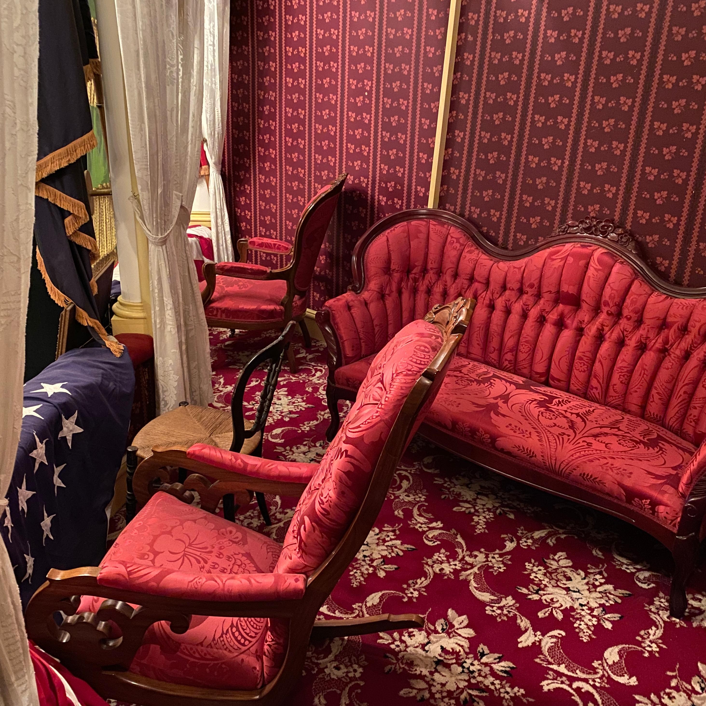 Theatre Box with red carpet, wallpaper, and red upholstered Victorian furniture.