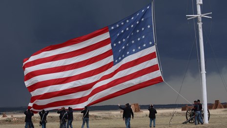 Soldiers lowering a large American flag.