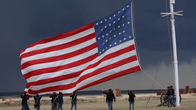Soldiers lowering a large American flag. 