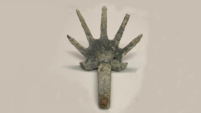 metallic object that looks like hands with spreading fingers attached to end of metal bar