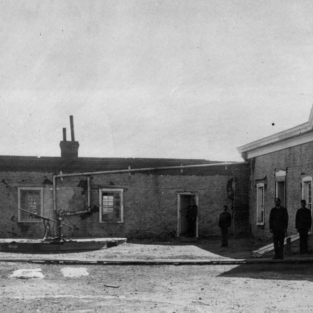 19th century hospital workers standing outside building with gutters leading to water tank