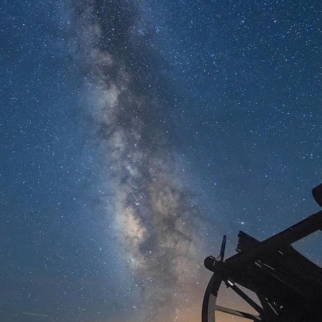 Star-filled sky with Milky Way visible across sky and cannon in foreground.