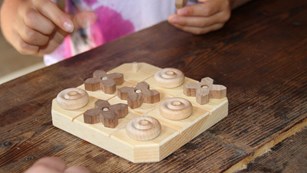 Child playing with wooden Tic-tac-toe board