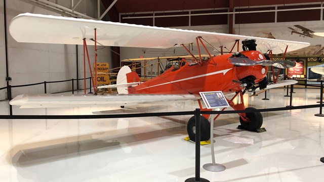 An orange and white biplane on display inside Pearson Air Museum.