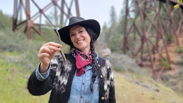 A woman holding a metal artifact and smiling at the camera.