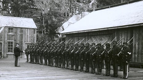 Photo of Black soldiers in uniform standing at attention.
