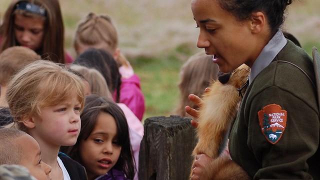 Photo of park ranger holding a fur with kids.