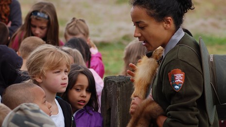 Photo of park ranger holding a beaver fur with children.