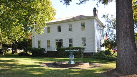 A white house sits in a grassy park.