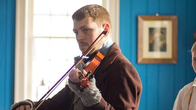 A man in 1840s clothing playing a violin.