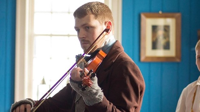 A man in 1840s clothing playing a violin.