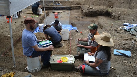Students and a National Park Service archaeologist at an excavation site.