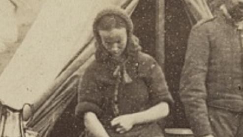 A black and white photo of a laundress in a Civil War-era camp.
