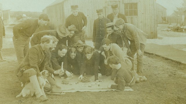 A black and white photo of soldiers playing a dice game.