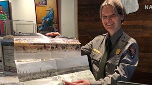 A park ranger in the Fort Vancouver Visitor Center holding up the park brochure.