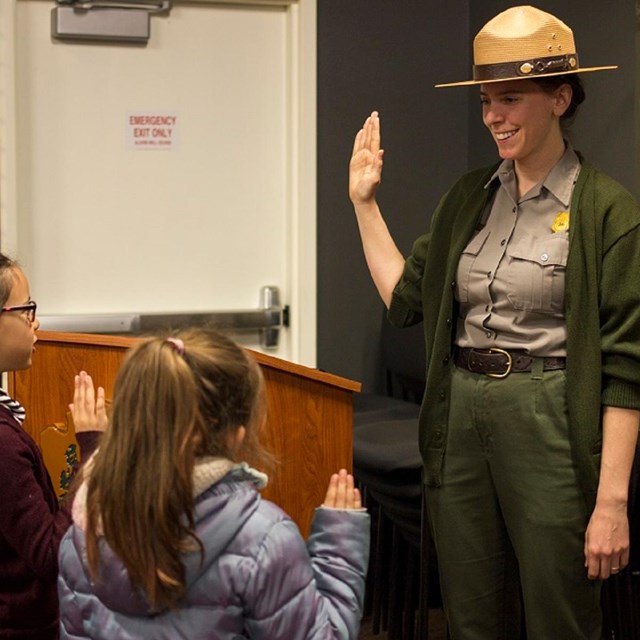 A park ranger swearing in two young junior rangers.