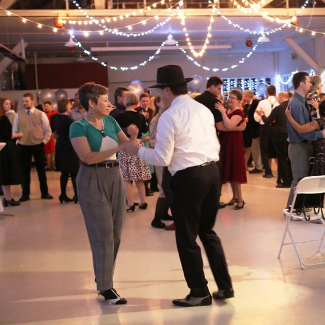 Couples dance to music from a live band inside the Historic Hangar at night.