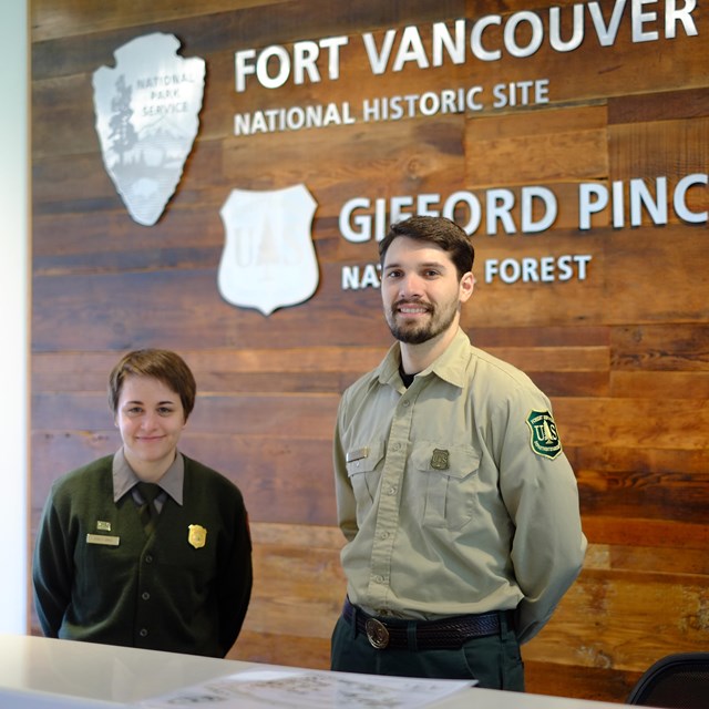 A national park ranger and a forest ranger inside the Fort Vancouver Visitor Center.