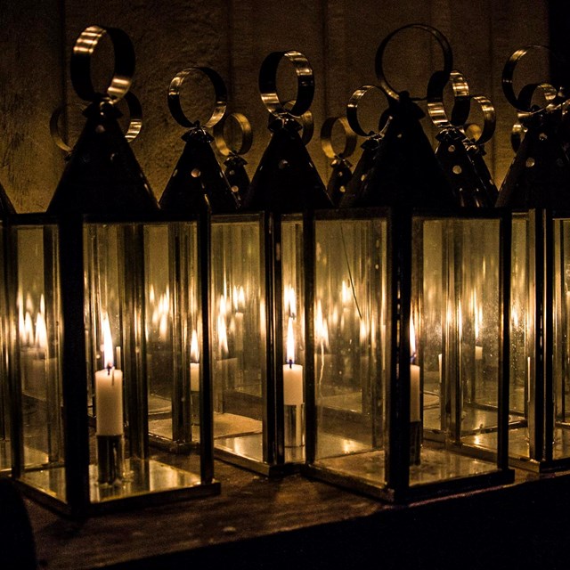 Many candle lanterns on a table.