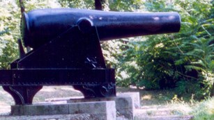 Large black iron cannon in the woods