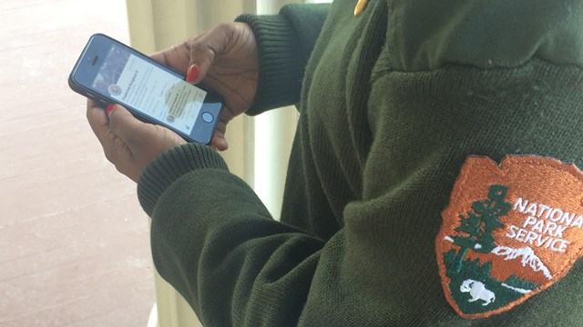 A ranger looks at social media on her smartphone